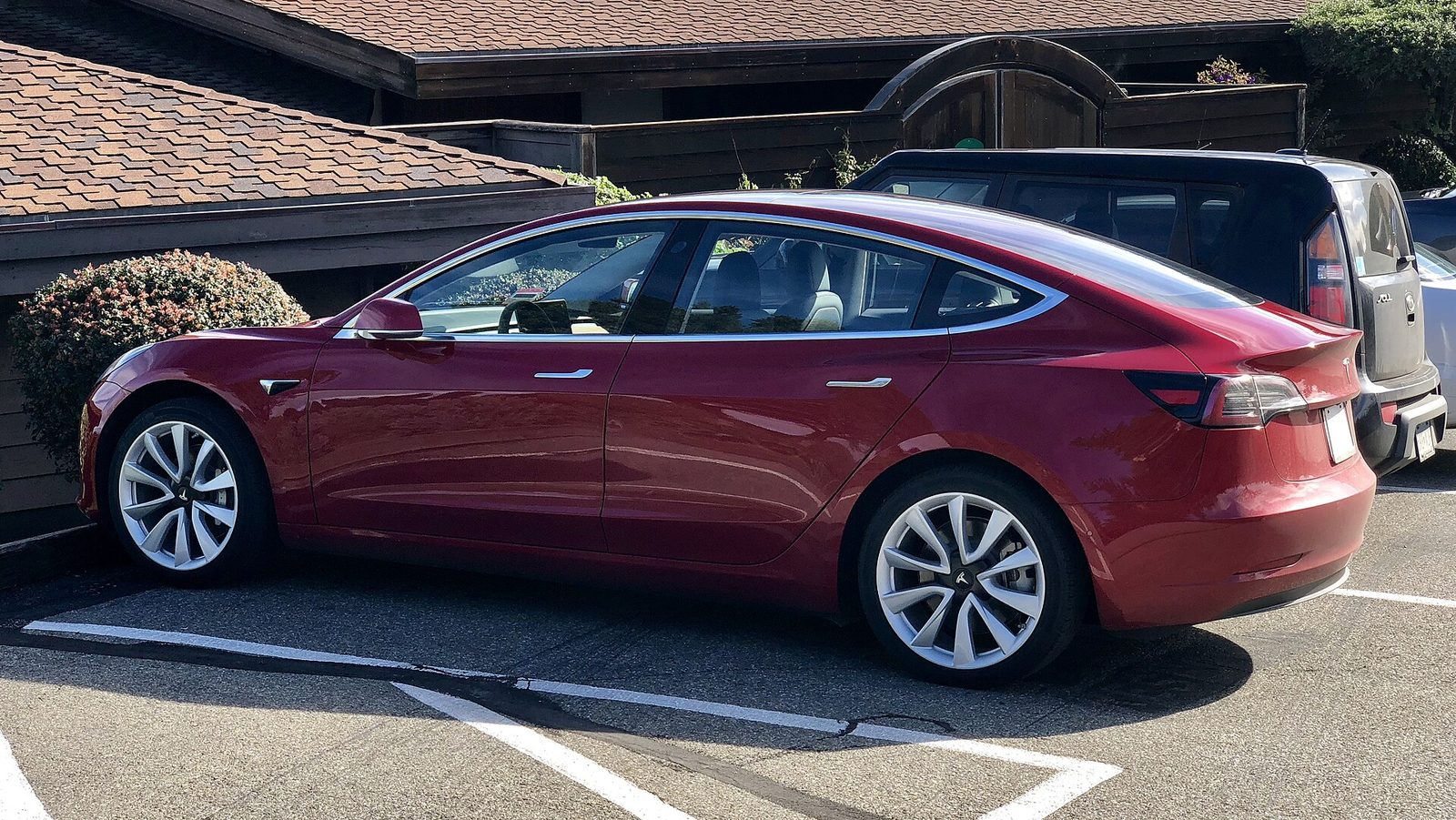 A Tesla Model 3 parked at the kerb on a residential street